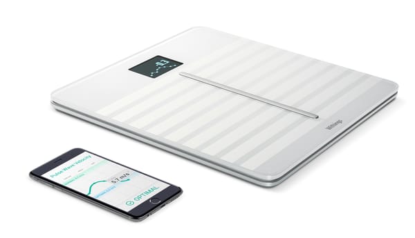 A white pair of bathroom scales with a small screen embedded on them, next to an iPhone old enough to have a home button.
